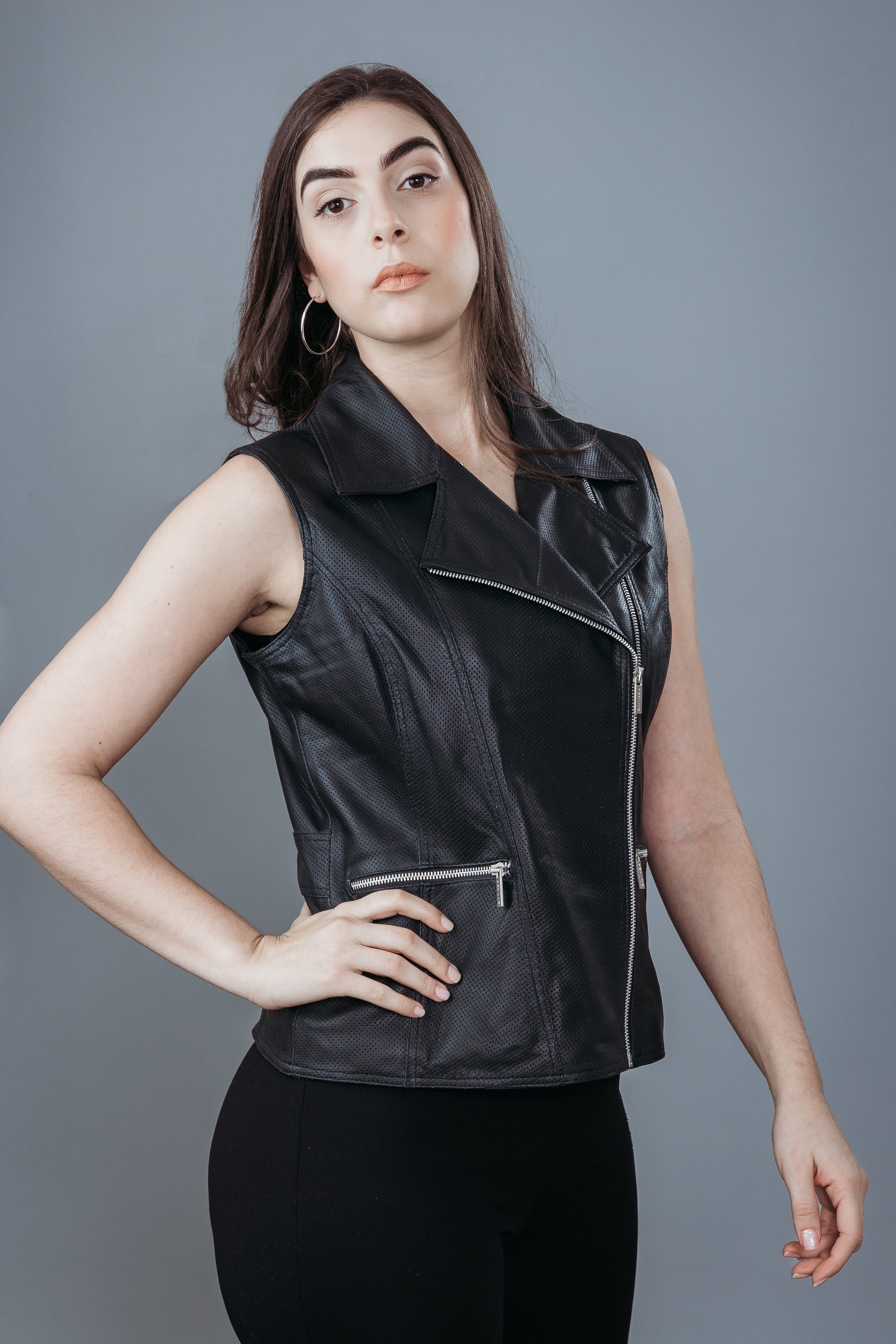 Women's Sleeveless Biker Jacket made with Perforate Semi Aniline Sheep Leather in Black Colour. Inner Lining is Silk Satin Material in Black Colour. It has Zipper and Matte Silver Trim.