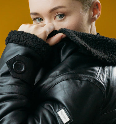 Woman Model Wearing Black Peroye Leather Jacket With Brown Background