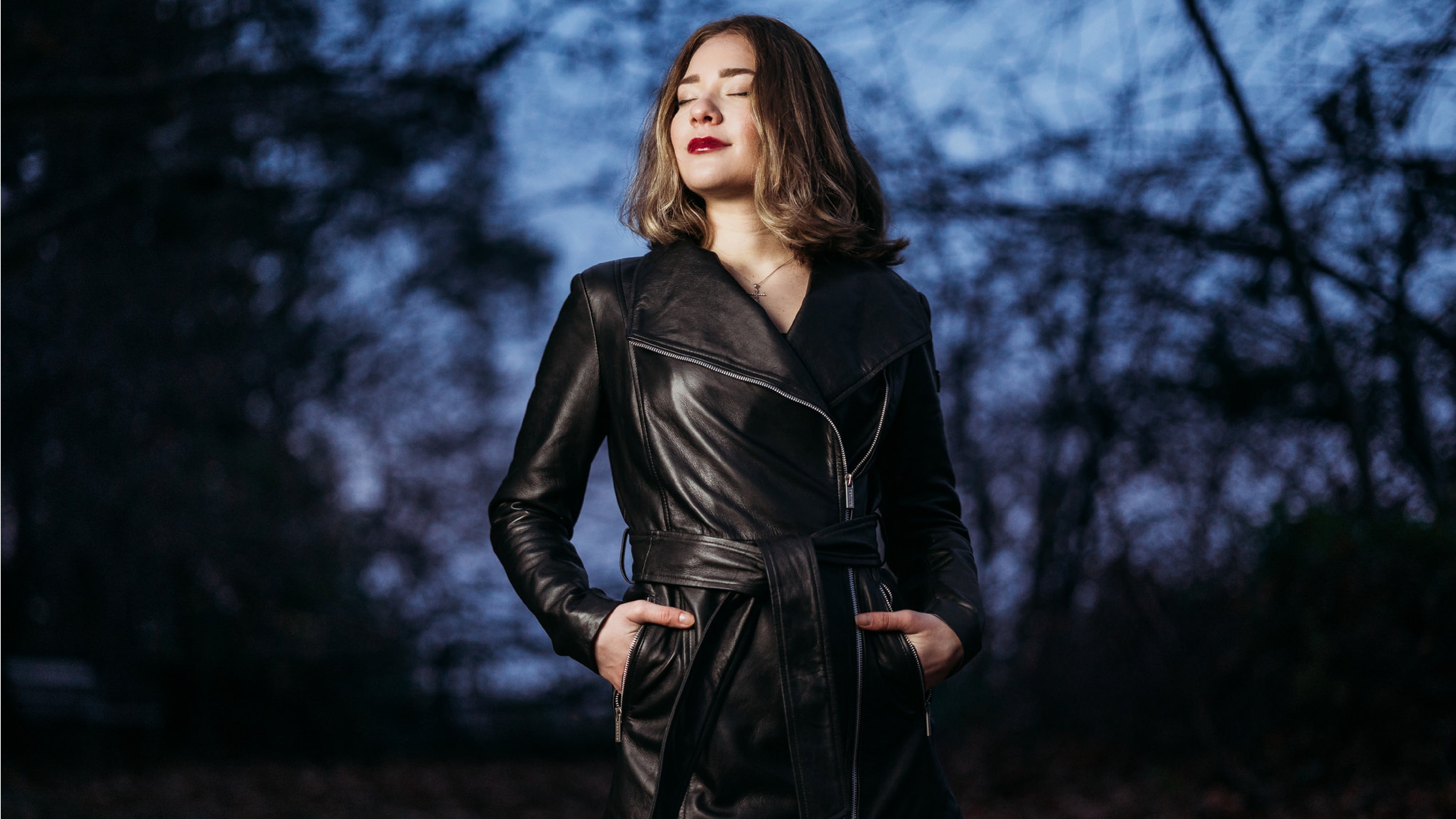 Female Model Wearing peroye leather jackets brand trench coat with trees in the dark background